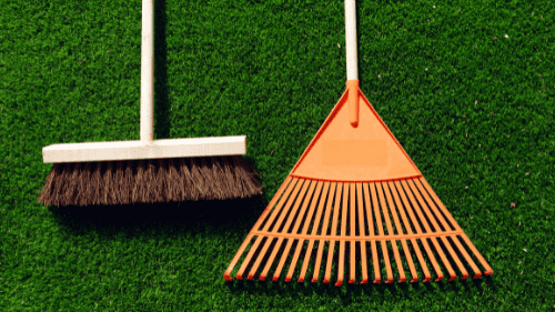 Broom and rake lying on artificial turf