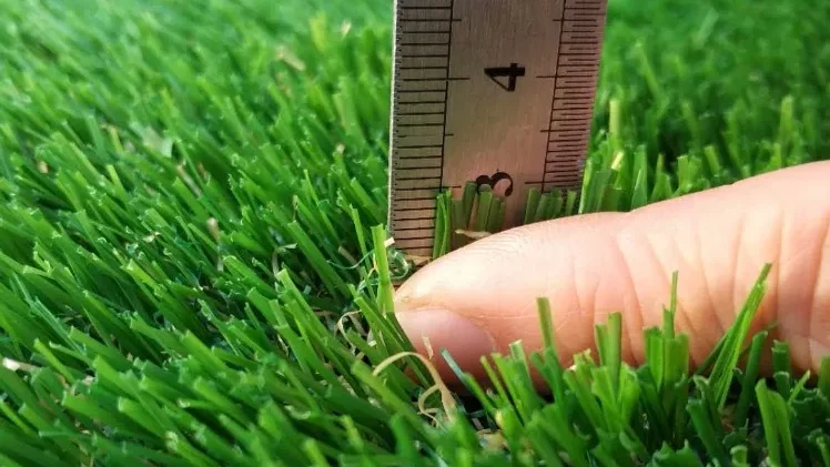 Ruler and finger showing pile height of artificial turf