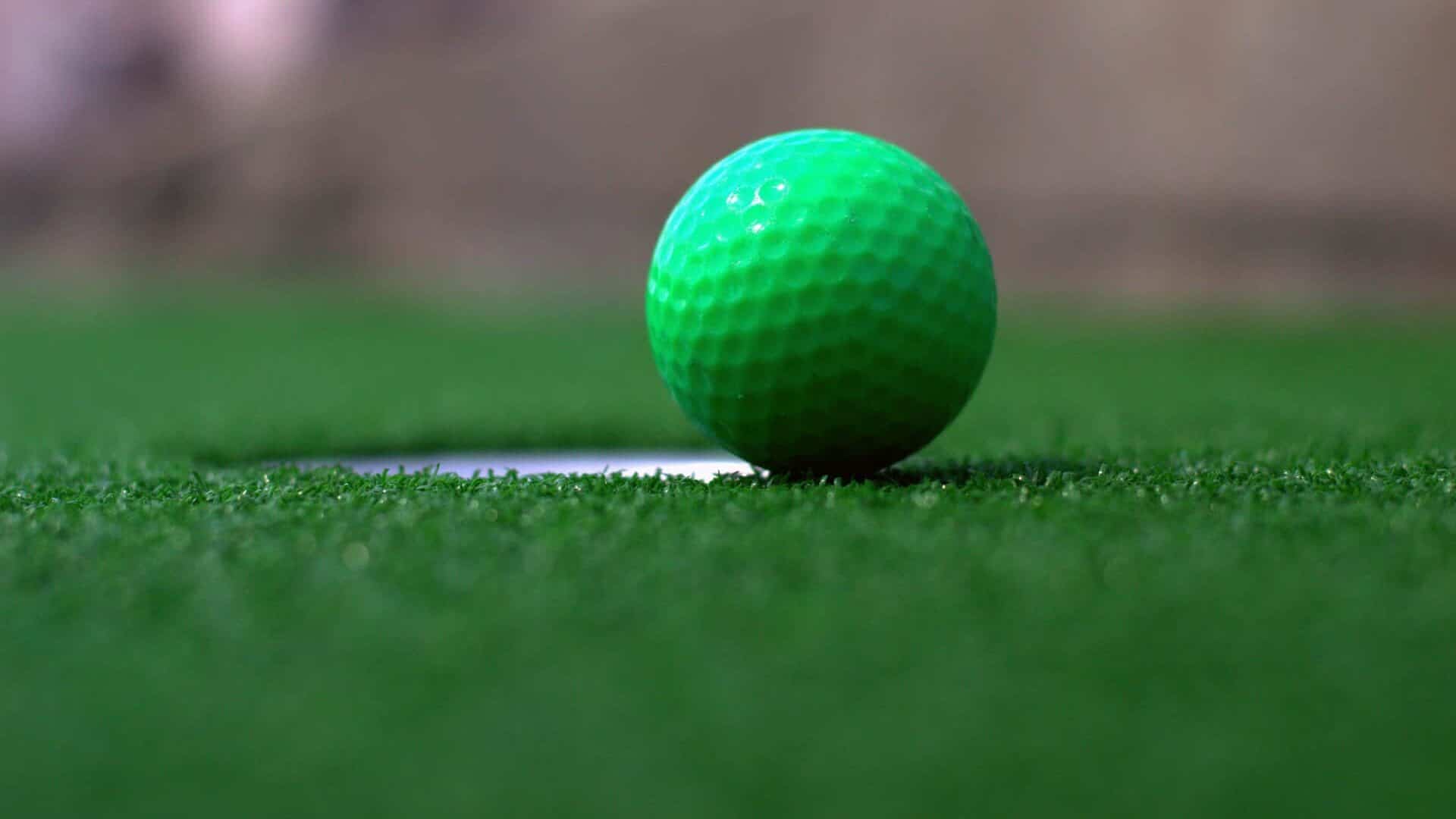Golf ball next to putting green hole