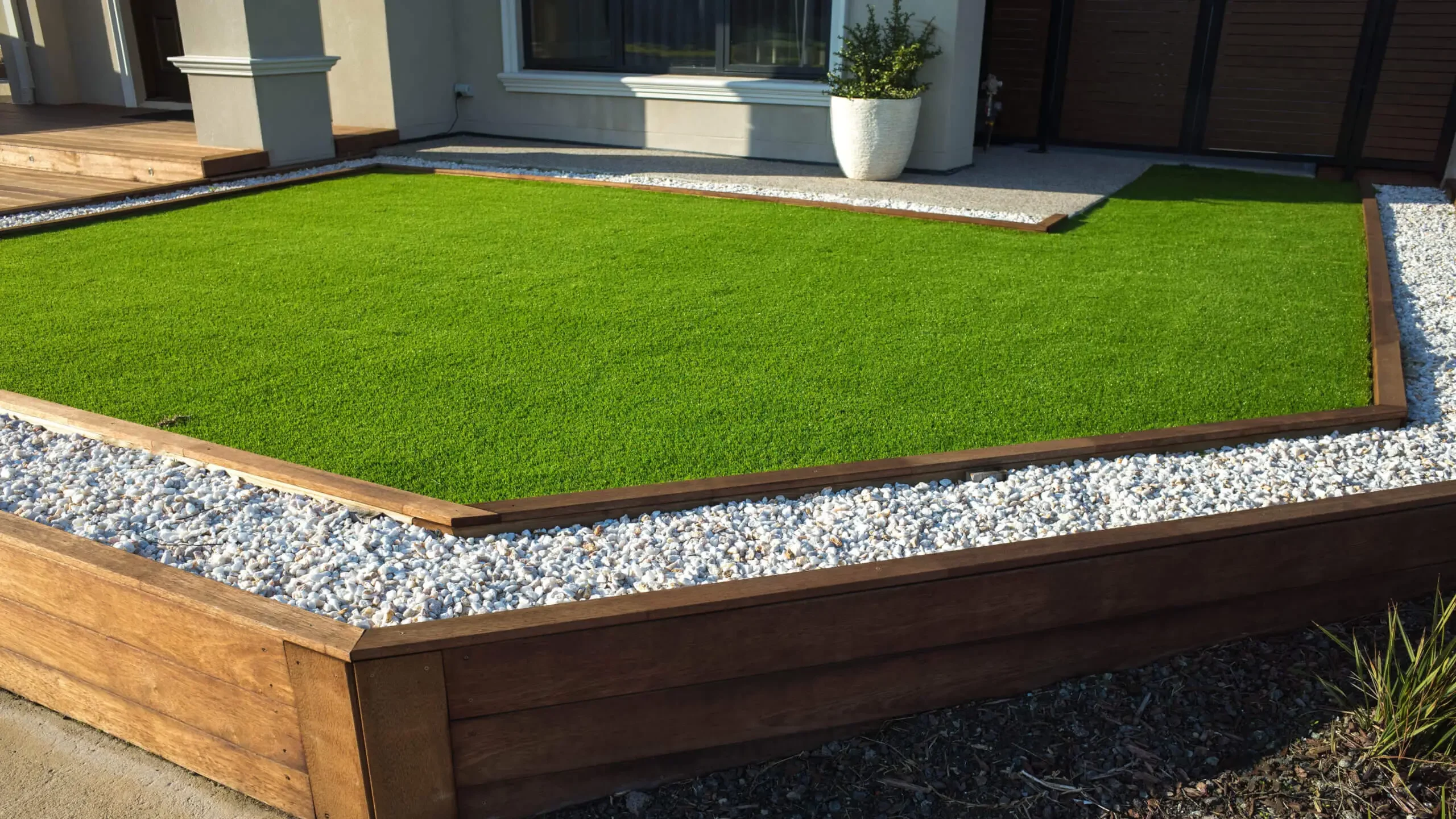Artificial turf front yard with wood and pebble edging
