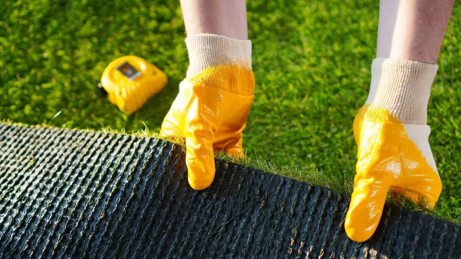 Installer showing rubber backing of artificial turf