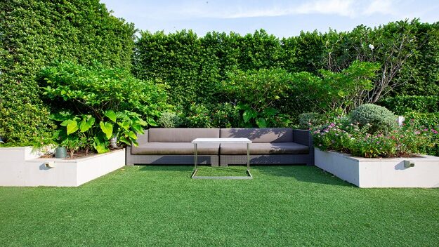 Rooftop garden with artificial grass and couch.